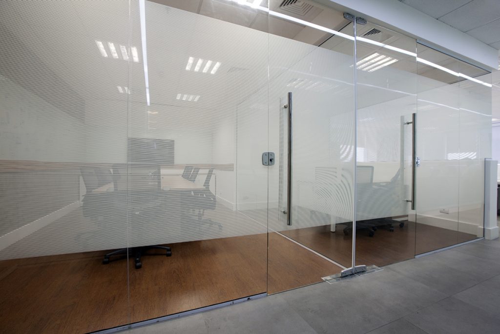 divisória de vidro para escritório com película jateada e porta de abrir